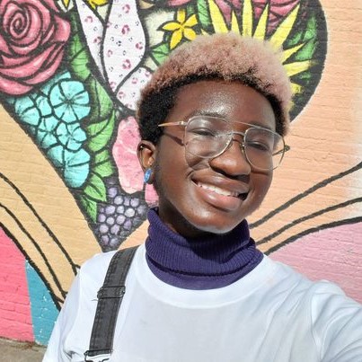 Picture of Lucien smiling in front of colorful artwork.